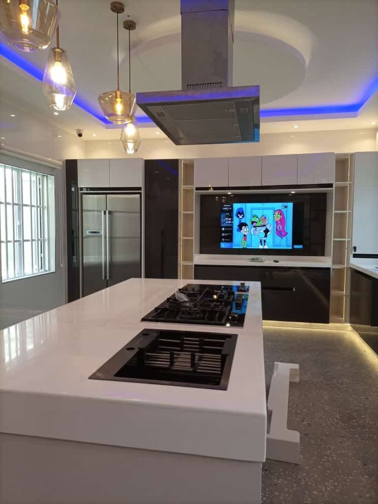 Island kitchen with white stone top, gas hob and pendant lights, built by Ebenshow