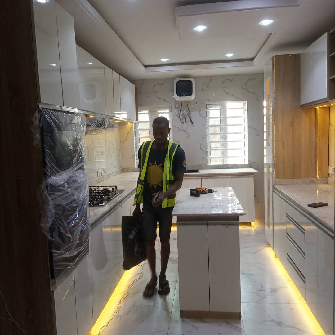 Ebenshow carpenter finishing a white gloss galley kitchen with a marble-top island